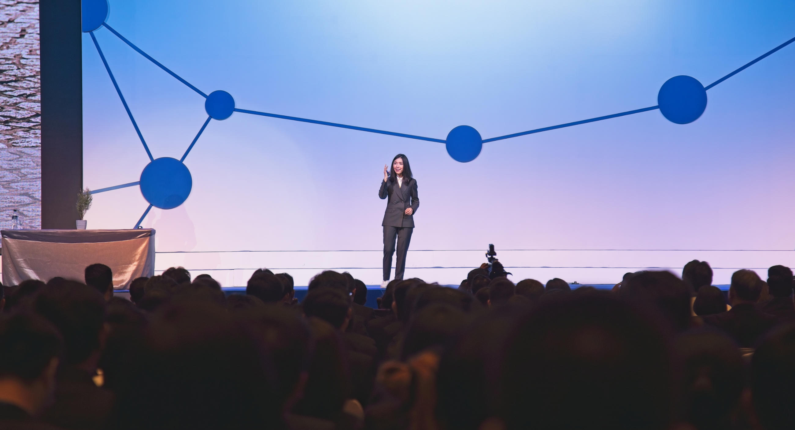 Speaker giving a speech on stage to a large audience